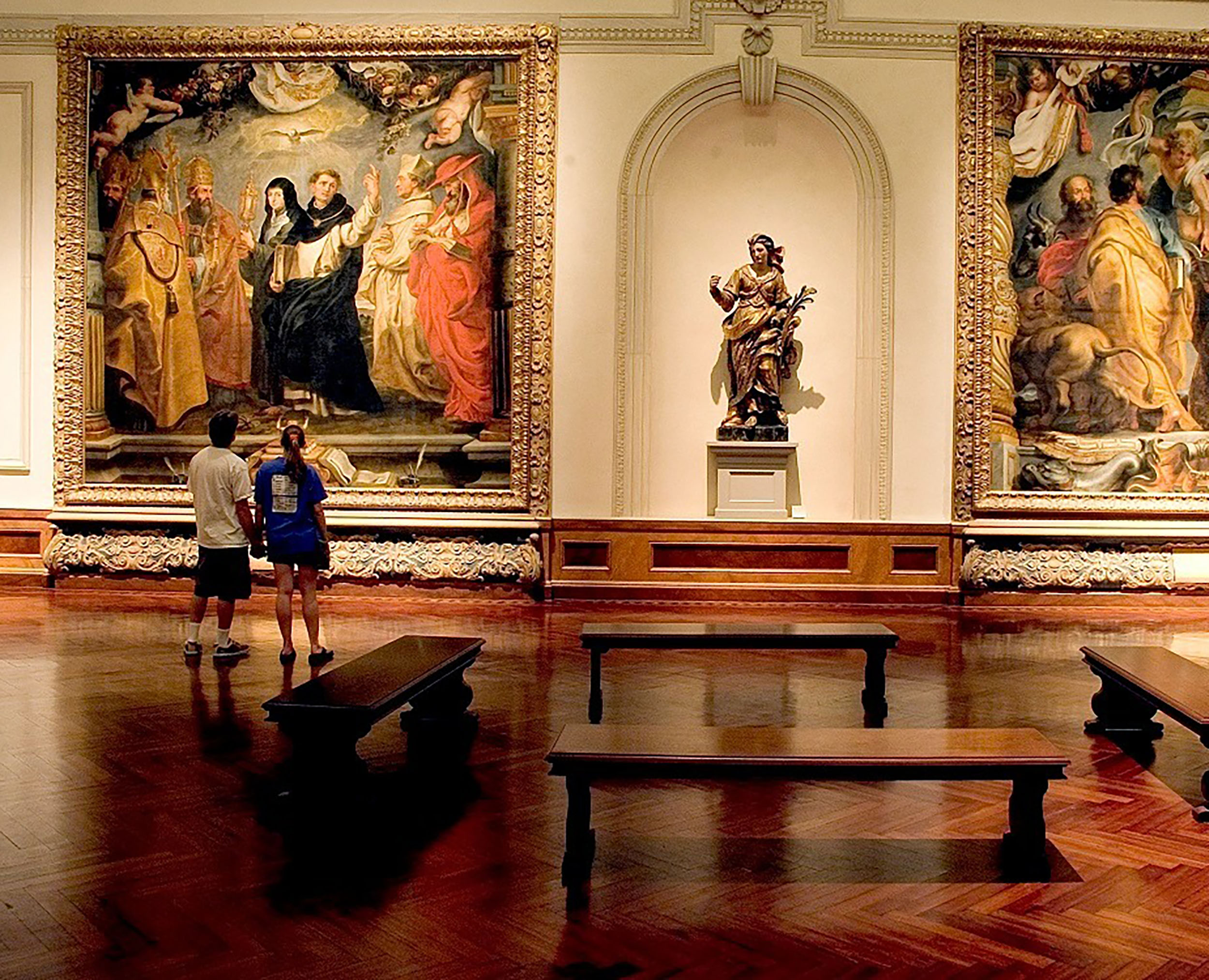 People view large religious renaissance paintings at the Ringling Art Gallery.
