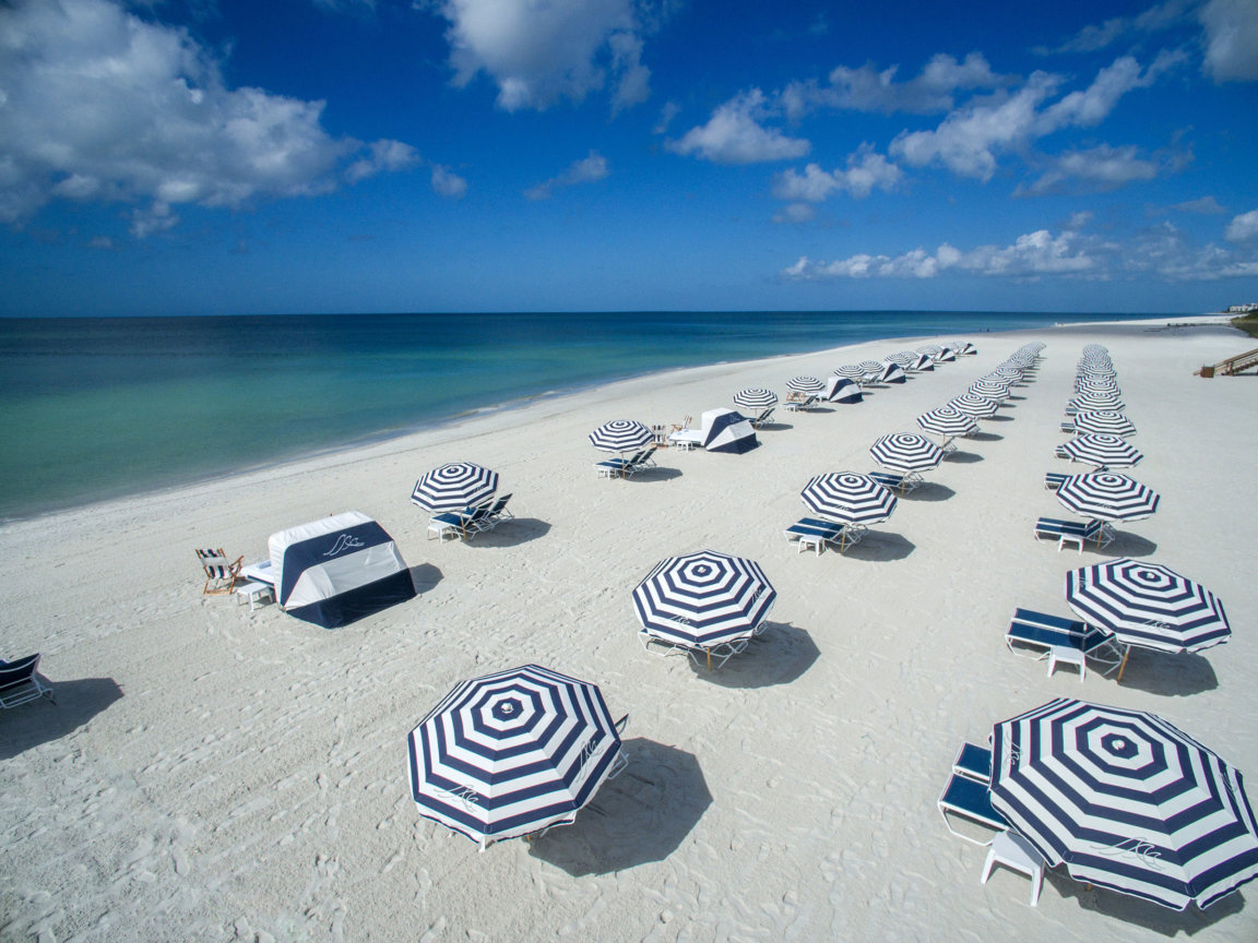 Aerial of blue and white stripped umbrellas and beach chairs at the Resort at Longboat Key Club.