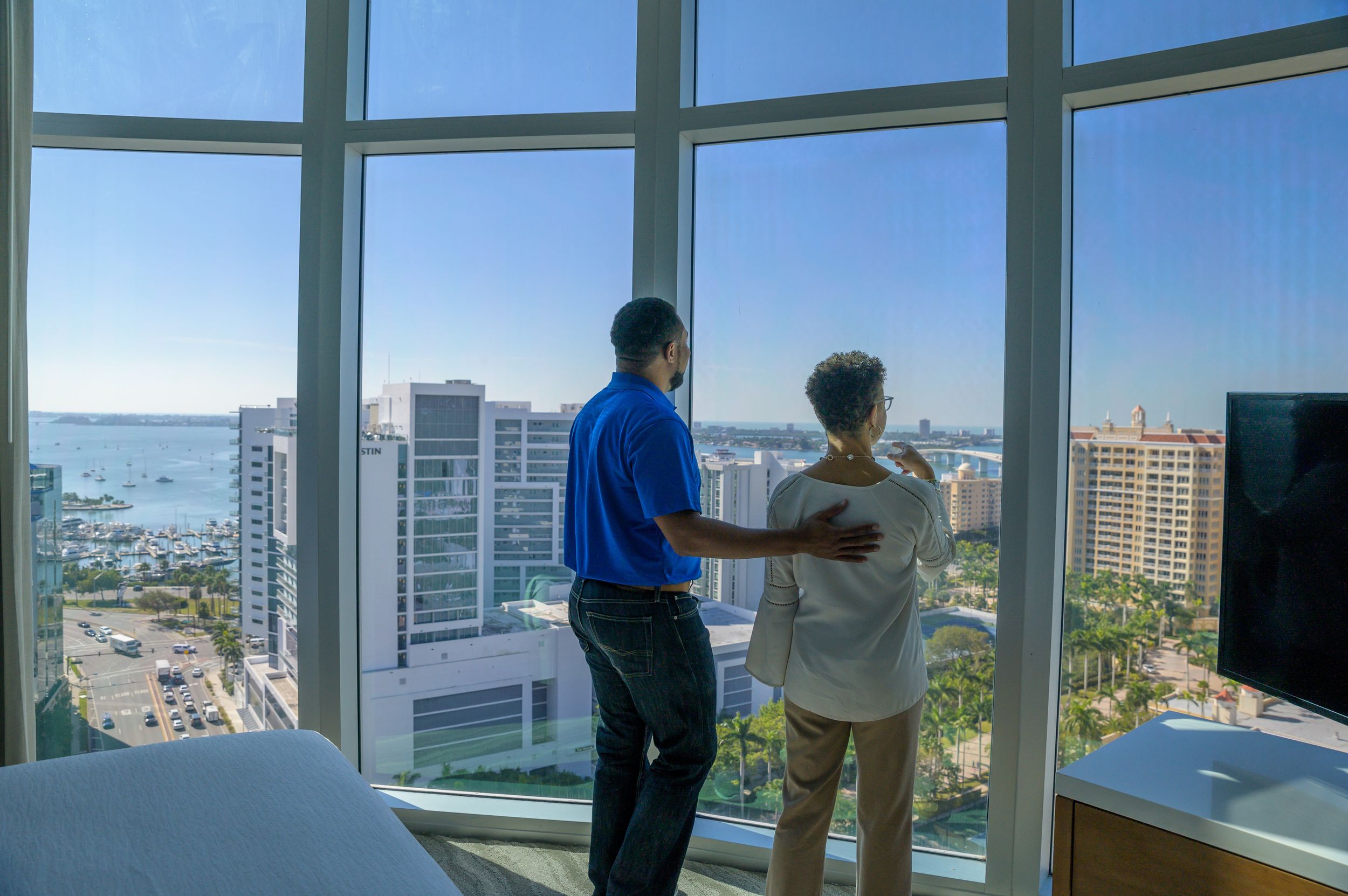 Two people in a high-rise apartment looking out the window at downtown Sarasota.