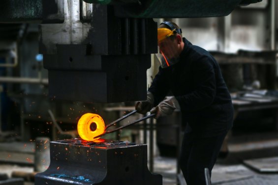 Man lifting hot metal in a factory