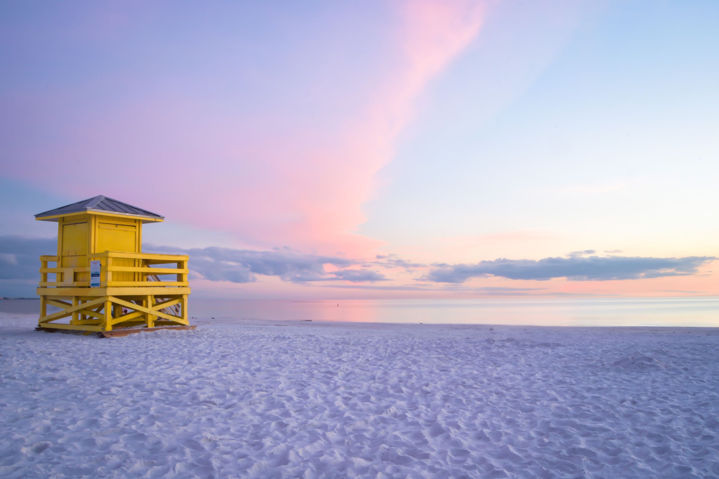 Yellow lifeguard tower on Siesta Key beach at sunset.