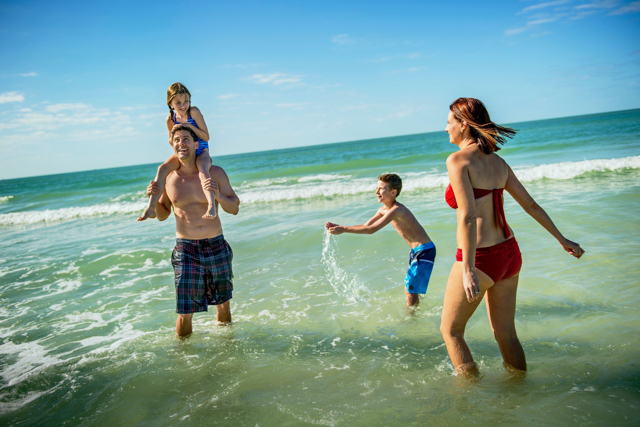 Four family members splash water in the ocean.